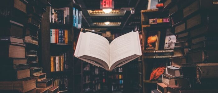 view of floating open book from stacked books in library