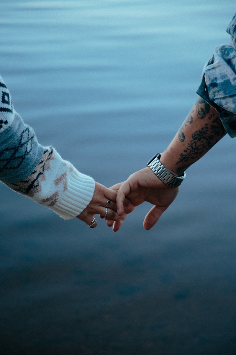 Two people holding hands by the water