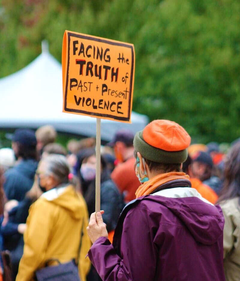 a man holding a sign that says facing the truth